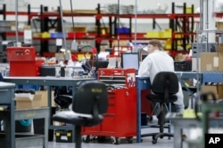 In this Oct. 24, 2017, photo, an employee wears his laboratory coat at his workstation at Lord Corporation, a manufacturer of industrial coatings, adhesives, bearings, and sensing equipment for range of commercial markets