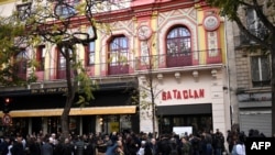FILE - People stand in front of the Bataclan concert venue during ceremonies across Paris on Nov. 13, 2017, marking the second anniversary of the terror attacks of Nov. 2015 in which 130 people were killed.