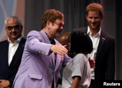 British musician Elton John embraces a participant as Britain's Prince Harry looks on during a panel "Breaking barriers of inequity in the HIV response" during the 22nd International AIDS Conference (AIDS 2018), the largest HIV/AIDS-focused meeting in the world, in Amsterdam, Netherlands, July 24, 2018.