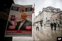 A man holds a poster showing images of Saudi Crown Prince Muhammed bin Salman (L), dubbed "assassin," and of journalist writer Jamal Khashoggi, dubbed "martyr," during a prayer service for Khashoggi, in Istanbul, Turkey, Nov. 16, 2018.