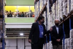 Orang-orang melihat dari jendela ketika Presiden AS Joe Biden mengunjungi Houston Food Bank didampingi oleh CEO-nya Brian Greene di Houston, Texas, AS, 26 Februari 2021. (Foto: REUTERS/Jonathan Ernst)