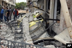 FILE - In this photo released by the Syrian official news agency SANA, Syrian citizens gather at the scene of an explosion in the central city of Homs, Syria, May 23, 2017.