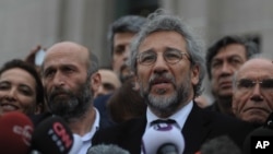 FILE - Can Dundar, the editor-in-chief of opposition newspaper Cumhuriyet, right, and Erdem Gul, left, the paper's Ankara representative, speak to the media after the opening of their trial in Istanbul, March 25, 2016.