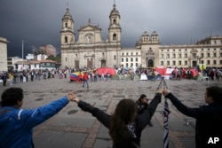 FILE - Demonstrators hold hands to support a peace accord between the Colombian government and rebels of the Revolutionary Armed Forces of Colombia, FARC, at the main square in Bogota, Colombia, Oct. 8, 2016.