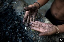 In this Nov. 30, 2017 photo, a river scavenger shows a silver cross he found at the bottom of the polluted Guaire River