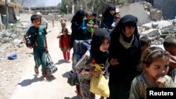 Displaced civilians walk towards the Iraqi Army positions after fleeing their homes due to clashes in the Shifa neighbourhood in western Mosul, Iraq, June 15 2017. 