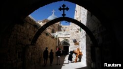 A priest kisses a cross near the Church of the Holy Sepulchre on Good Friday during Holy Week in Jerusalem's Old City, Mar. 29, 2013. 