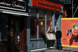 A man looks at the menu of a closed Chinese restaurant in Chinatown, in London, May 9, 2020.