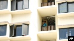 A foreign worker talks on the phone outside his room at the WestLite Toh Guan dormitory after it was declared an isolation area under the Infectious Diseases Act, April 10, 2020. (AP Photo/Yong Teck Lim)