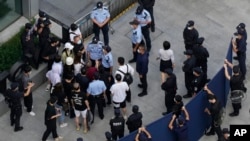 Investors are surrounded by police and security personnel as they try to enter the headquarters of the real estate developer Evergrande Group, Sept. 23, 2021, in Shenzhen, China. 