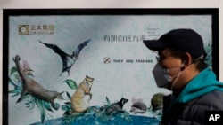 Seorang pria mengenakan masker berjalan melewati poster kampanye perlindungan satwa liar di tengah wabah virus corona di in Beijing, China, 11 Maret 2020. 