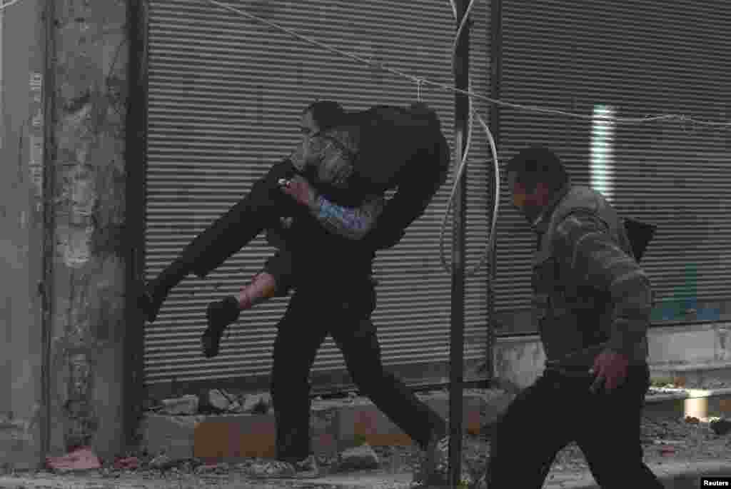 Fighters from the Free Syrian Army's Al Rahman legion help a wounded comrade in Mleha suburb of Damascus, April 2, 2014. 