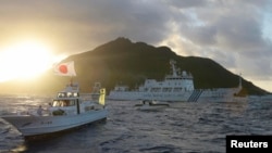 Chinese marine surveillance ship Haijian No. 51 (C) sails near Japan Coast Guard vessels (R and L) and a Japanese fishing boat (front 2nd L) as Uotsuri island, one of the disputed islands, called Senkaku in Japan and Diaoyu in China, is in background, Jul