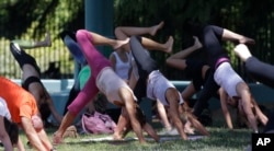 FILE - People perform yoga to mark International Yoga Day, in Milan, Wednesday, June 21, 2017. (AP Photo/Luca Bruno)