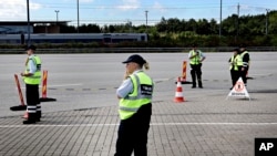 FILE - Danish customs officials stand ready at the Danish border to Sweden at on the Oeresund Bridge, Denmark, July 5, 2011. 