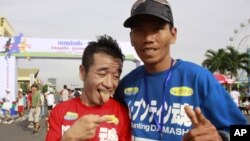 Japanese entertainer Neko Hiroshi, left, poses with Cambodian winner Em Buntin after a half marathon Saturday, June 18, 2011 in Phnom Penh, Cambodia. The Japanese finished second. More than 1,000 Cambodians and foreigners took part in the running, celebra