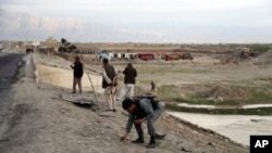 Seorang anggota pasukan keamanan Afghanistan memungut selongsong peluru setelah serangan dekat Pangkalan Udara Bagram di utara Kabul, Afghanistan, 9 April 2019. 
