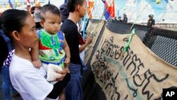 Supporters gather in front of banners which read " FILE - Please provide justice to land activists of Boeung Kak," at a blocked main street near Phnom Penh Municipality Court in Phnom Penh, Cambodia, Friday, May 30, 2014. 
