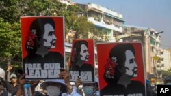 FILE - Anti-coup protesters display pictures of deposed Myanmar leader Aung San Suu Kyi in Yangon, Myanmar, March 2, 2021. 