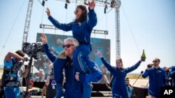 ស្ថាបនិក​ក្រុមហ៊ុន​អាកាសចរណ៍ Virgin Galactic លោក Richard Branson លើក​អវកាសយានិក​ម្នាក់​របស់​លោក​ គឺ​អ្នកស្រី Sirisha Bandla ដាក់​លើ​ស្មា ខណៈ​ដែល​ពួកគេ​សាទរ​នឹង​ដំណើរ​ជោគជ័យ​ទៅ​កាន់​អវកាស​របស់​ខ្លួន​ ទីក្រុង Truth or Consequences រដ្ឋ New Mexico ថ្ងៃទី១១ ខែកក្កដា ឆ្នាំ២០២១។