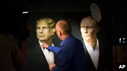 A journalist points at a portrait of U.S. President-elect Donald Trump, with a portrait of Russian President Vladimir Putin at right, during a live telecast of the U.S. presidential election in the Union Jack pub in Moscow, Russia, Nov. 9, 2016. 