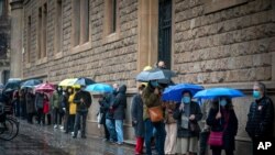 People line up outside a polling station, before casting their vote for the regional Catalan election in Barcelona, Spain, Feb. 14, 2021.