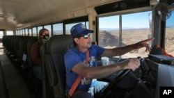 FILE - School bus driver by Kelly Maestas travels along a dirt road, with social worker Victoria Dominguez, outside Cuba, N.M., Oct. 19, 2020. The switch to remote learning in rural New Mexico has left some students profoundly isolated.