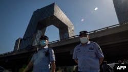 两名警察在北京街头巡逻，背景是中国中央电视台大楼。（2020年5月19日）