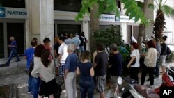 People stand in a queue to use ATMs of a bank in central Athens, Sunday, June 28, 2015.