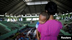 Seorang perempuan menggendong anaknya di sebuah aula olahraga di daerah Klungkung, Bali, yang menjadi pusat evakuasi sementara bagi warga yang tinggal di dekat Gunung Agung, 28 September 2017. (REUTERS/Darren Whiteside).