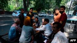 FILE - People gather to make calls at a makeshift phone booth set up by Indian security forces outside a camp during a lockdown in Srinagar, Sept. 3, 2019.