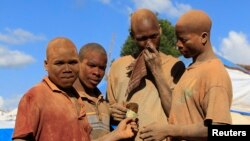 FILE - Youths covered in dust work at an open-pit gold mine in Lukingi village in Mubende district, about 150 km (90 miles) southwest of Uganda's capital Kampala.