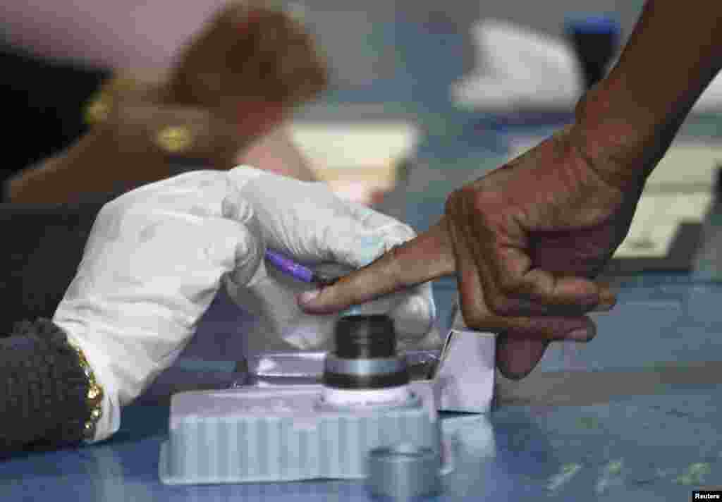 Petugas di tempat pemungutan suara menyapu jari pemilih&nbsp;dengan cat sebelum yang bersangkutan memberikan suara dalam pemilihan umum di Permatang Pauh (5/5). 