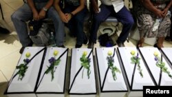 Relatives sit next to the remains of 11 victims of the El Mozote massacre during a ceremony at the Supreme Court of Justice in San Salvador, El Salvador May 20, 2016.