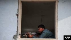 An Afghan policeman takes position at the site of a suicide attack in Jalalabad, March 26, 2012.
