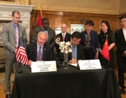 FILE - Arkansas Gov. Asa Hutchinson, center left, and Shandong Ruyi Technology Group Chairman Yafu Qiu sign a memorandum of understanding in Little Rock, Ark., May 10, 2017, for a $410 million facility the textile company plans to open in Arkansas.