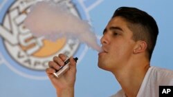 FILE - A smoker exhales vapor from an e-cigarette at the Vapor Spot, in Sacramento, California, in this July 7, 2015, photo.