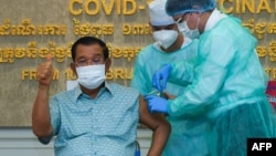 លោកនាយករដ្ឋមន្ត្រី ហ៊ុន សែន លើកមេដៃបង្ហាញអ្នកសារព័ត៌មាន ខណៈលោកទទួលចាក់វ៉ាក់សាំងបង្ការជំងឺកូវីដ១៩ របស់ក្រុមហ៊ុន AstraZeneca នៅមន្ទីរពេទ្យកាល់ម៉ែត្រ រាជធានីភ្នំពេញ ថ្ងៃទី៤ ខែមីនា ឆ្នាំ២០២១។