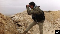 In this photo, which has been authenticated based on its contents and other AP reporting, a Syrian rebel looks through his binocular at one of the frontline of Yabroud town, the last rebel stronghold in Syria's mountainous Qalamoun region, Mar. 13, 2014. (Photo taken and provided by Local Comity of Yabroud Town)