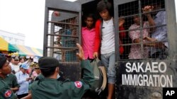 Cambodian migrant workers get off from a Thai truck upon their arrival from Thailand at Cambodia-Thai international border gate in Poipet, Cambodia, Tuesday, June 17, 2014.
