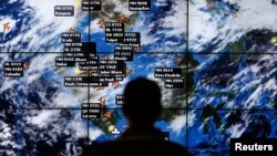 បុរស​ម្នាក់​ពិនិត្យ​មើល​អេក្រង់​ធំ​មួយ​​នៅ​អាកាសយានដ្ឋាន​អន្តរជាតិ​គូឡាឡាំពួ​ ដែល​បង្ហាញ​ជើង​​យន្តហោះ​ផ្សេងៗ​ដែល​កំពុង​​​​នៅ​លើ​អាកាស​ថ្ងៃ​ទី​១៣ ខែ​មីនា ឆ្នាំ​២០១៤។