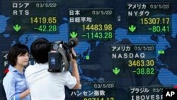 Seorang juru kamera tengah menyoroti indikator elektronik yang terpampang di luar gedung sebuah perusahaan sekuritas di Tokyo (23/5). Indeks Nikkei Jepang turun tajam sebanyak 7,3 persen dan berakhir dengan 1.143 poin lebih rendah dibandingkan saat pembukaan lantai bursa di pagi harinya.