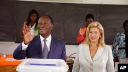 FILE - Ivory Coast’s president Alassane Ouattara, left, waves after casting his ballot with his wife, Dominique Ouattara, right, at a polling station during elections in Abidjan, Ivory Coast, Sunday Oct. 25, 2015. 