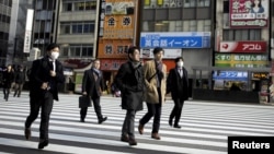 People cross a street in a business district in Tokyo, Japan.