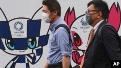 People walk by posters to promote the Olympic Games planned to start in the summer of 2021, in Tokyo, June 16, 2021. 