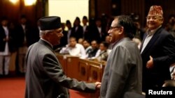 尼泊尔总理奥利（左）在议会宣布辞职后与尼泊尔共产党主席普拉昌达握手