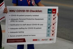 Lizette Torres holds a sign while fellow nurse and union member Tishna Soto, speaks to reporters as the prepare a small protest outside their work at the Las Palmas Del Sol Medical Center on April 1, 2020, in El Paso, Texas.