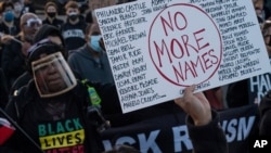 A demonstrator holds up a sign bearing the names of people who died during police incidents, during a protest over the fatal shooting of Daunte Wright during a traffic stop, in Brooklyn Center, Minnesota, April 16, 2021.