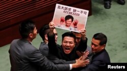 Anggota DPR pro-demokrasi dikawal petugas keamanan dari Gedung DPR Hong Kong, saat Pemimpin Eksekutif Hong Kong Carrie Lam menjawab pertanyaan anggota DPR di Hong Kong, China, 17 Oktober 2019. (Foto: Reuters)