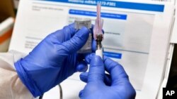 FILE - A nurse prepares a shot as the world's biggest study of a possible COVID-19 vaccine, developed by the National Institutes of Health and Moderna Inc., gets under way in Binghamton, N.Y., July 27, 2020.